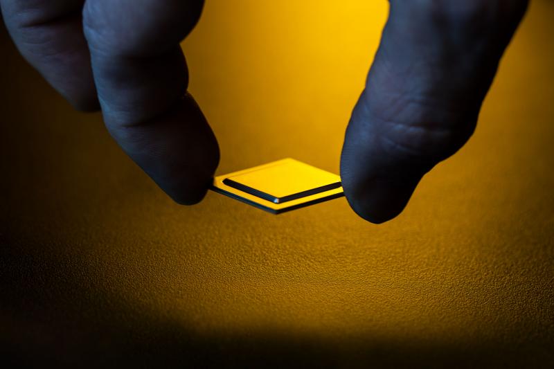 mão segurando um chip, luz de fundo amarela