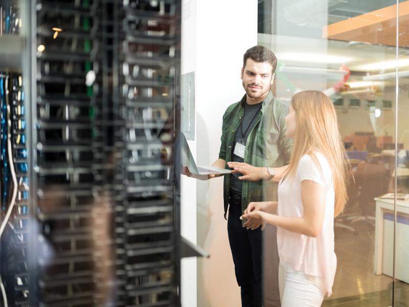 Man and woman talking next to server rack