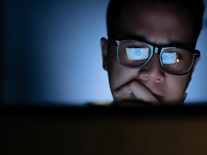 focused man with glasses looking at a computer screen