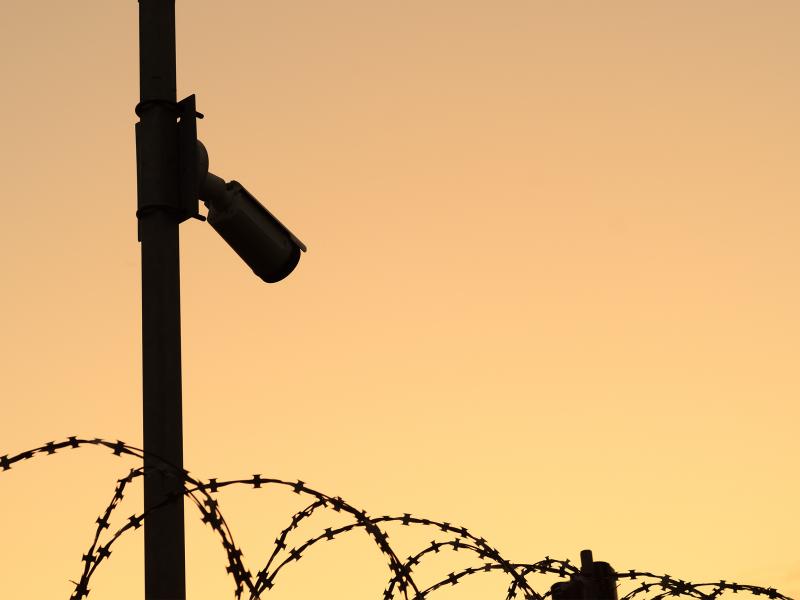 Camera on a pole by a fence 