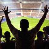 Silhouettes of spectators looking out over a soccer stadium