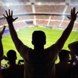 Silhouettes of spectators looking out over a soccer stadium 